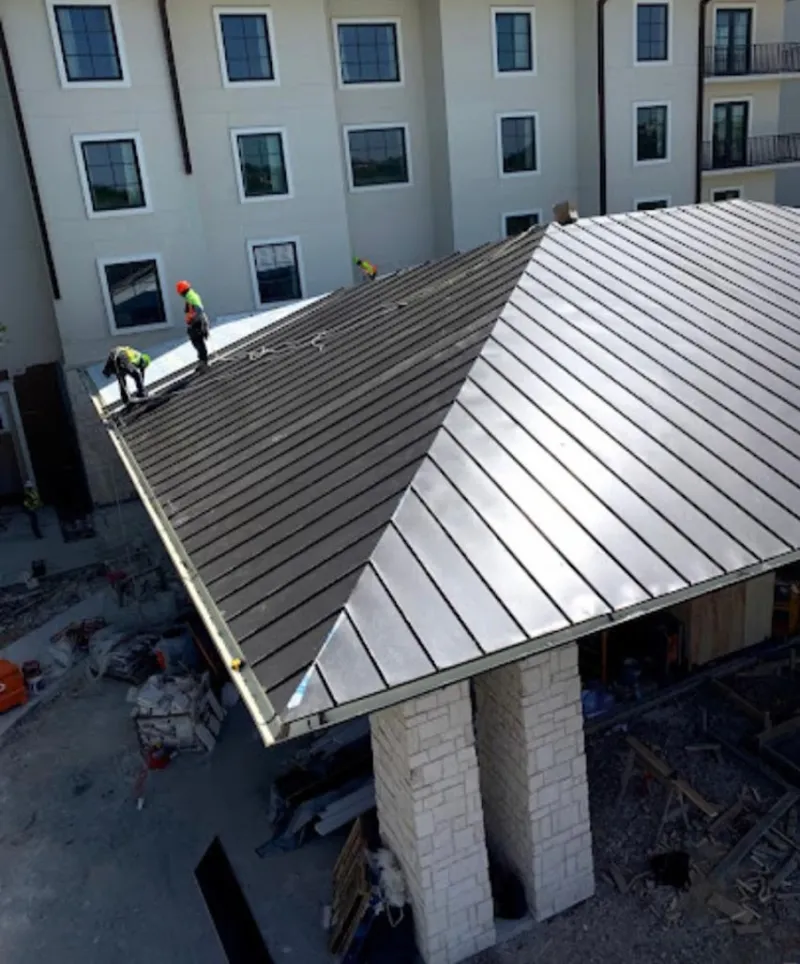 Crew installing standing seam metal roof panels on a commercial project in Finneytown